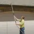 Man in front of his garage using GutterJet to clean his gutters